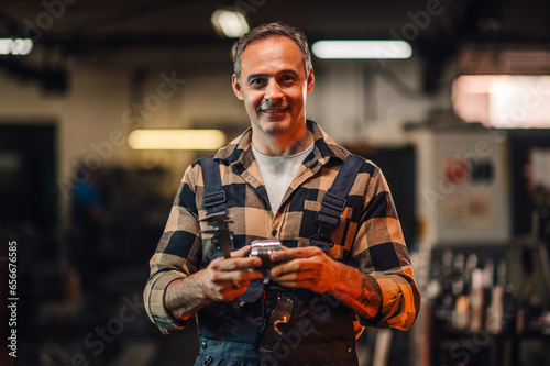 A portrait of a metallurgist holding a metal part and a measuring tool. photo