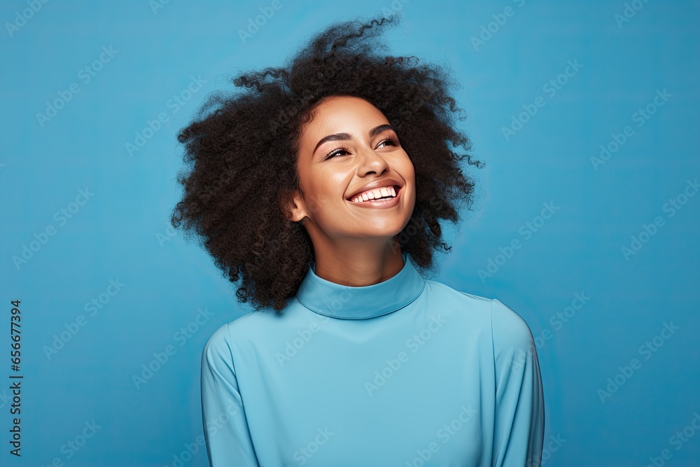 Young African American woman with a cheerful smile and stylish afro hair on a blue background. Young African American woman with a cheerful smile and stylish afro hair on a blue background.