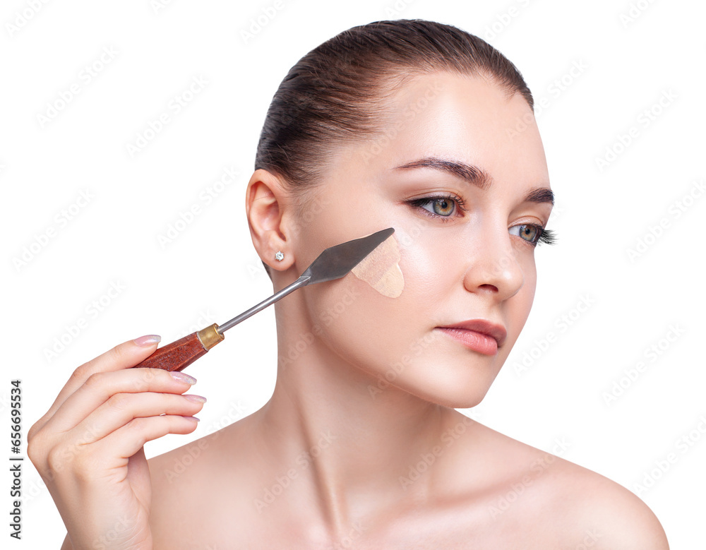Young woman applying foundation with artistic spatula.
