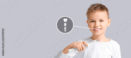 Little boy with dental implant brushing teeth on grey background