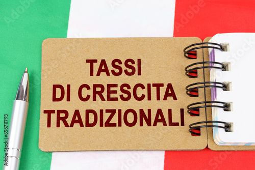 On the flag of Italy lies a pen and a notebook with the inscription - traditional growth rates photo