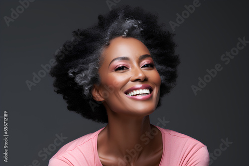 Smiling black adult woman touch face with smooth healthy skin. Open healthy smiling beautiful aging mature woman with white teeth. Beauty, dental and cosmetics skincare advertising concept.