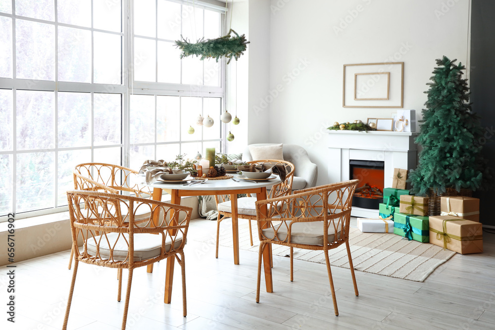Obraz premium Interior of light living room with Christmas tree, fireplace and served dining table