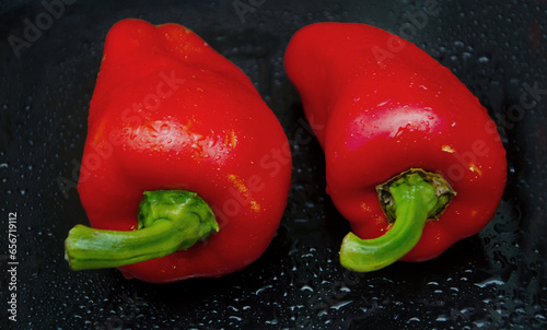 Red pepper. Several ripe red bell peppers with dew drops on a dark background, vegetables, sweet pepper