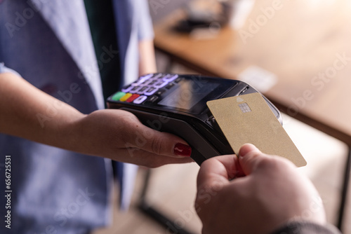 NFC credit card payment. Woman paying with contactless credit card with NFC technology. Wireless money transaction. Card machine in male hand on sunlight background © st.kolesnikov
