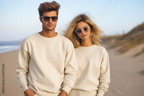 Man and woman wearing sunglasses standing on beach. photo