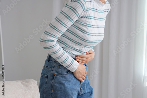 Young woman suffering from stomach ache at home, closeup