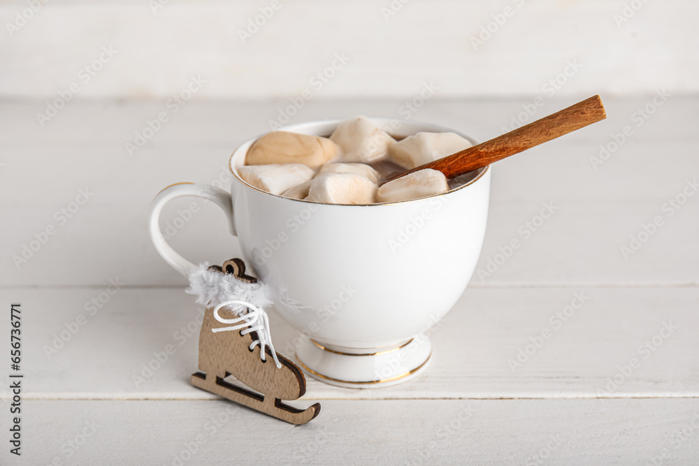Cup of tasty Christmas cocoa with marshmallows, cinnamon and skates on white wooden background Cup of tasty Christmas cocoa with marshmallows, cinnamon and skates on white wooden background
