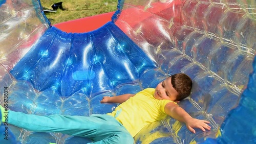 A small seven-year-old child boy runs and has fun in an aquazorb cylinder in the water of a pool in an amusement park. photo