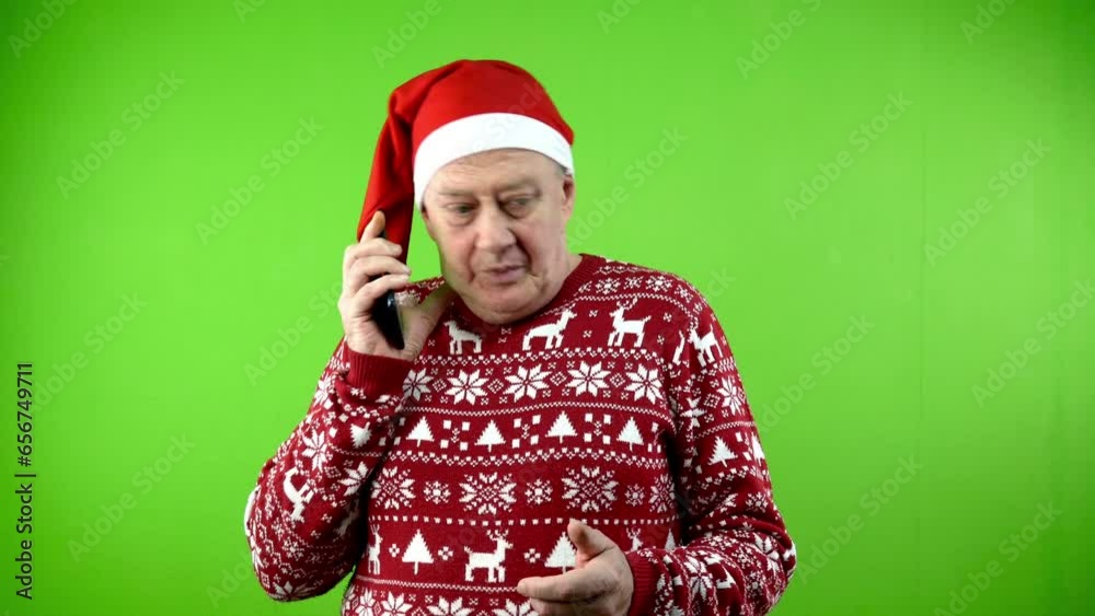 Senior man in red Santa hat and Xmas sweater walking talking on phone. Senior man in red Santa hat and Xmas sweater walking talking on phone.