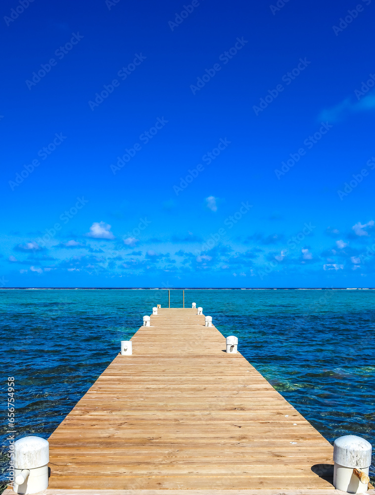 Boardwalk in Grand Cayman Cayman Islands stretching into the pristine blue green turquoise water of the Caribbean sea ocean view blue sky