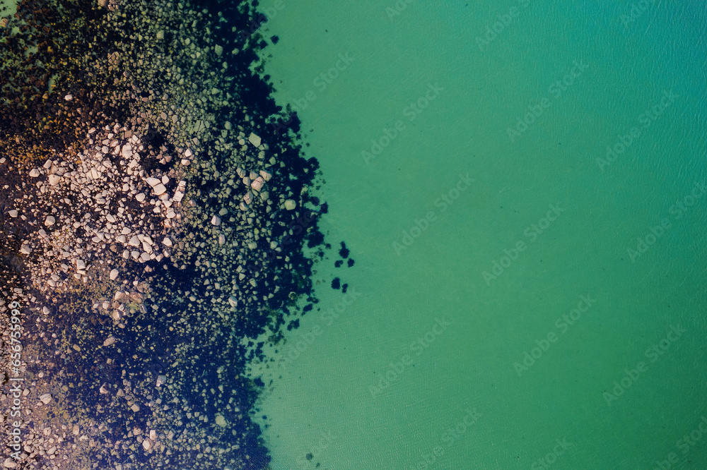 Aerial top down view on rough stone coast with green color water. Nobody. Nature shapes and forms.
