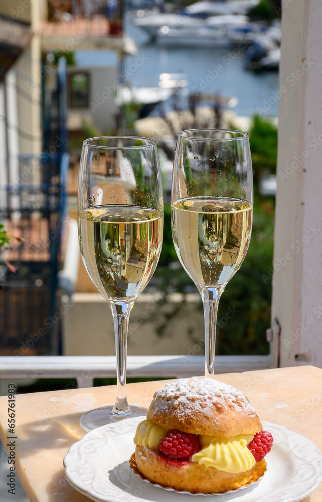 Drinking of French brut champagne sparkling wine with cake Tarte Tropezienne, club party in yacht harbour of Port Grimaud near Saint-Tropez, French Riviera vacation, France