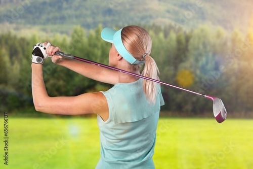 Young sporty female golfer player hitting ball