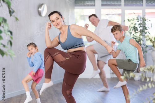 Joyful middle-aged woman training dance positions with her family members during workout session