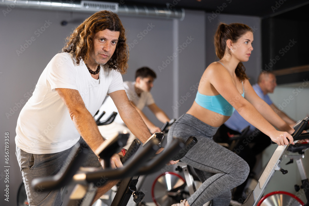 Motivated man leading healthy active lifestyle doing cardio workout on exercise bike in gym..