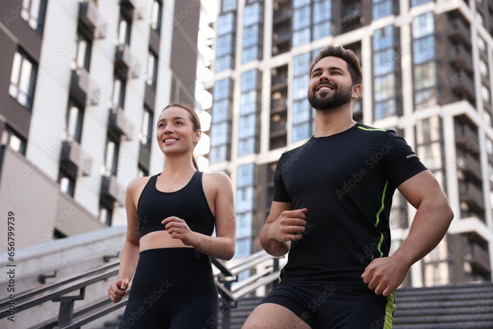 Healthy lifestyle. Happy couple running on steps outdoors, low angle view