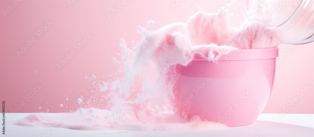 Pink background containing washing powder poured from a container for clothes Pink background containing washing powder poured from a container for clothes