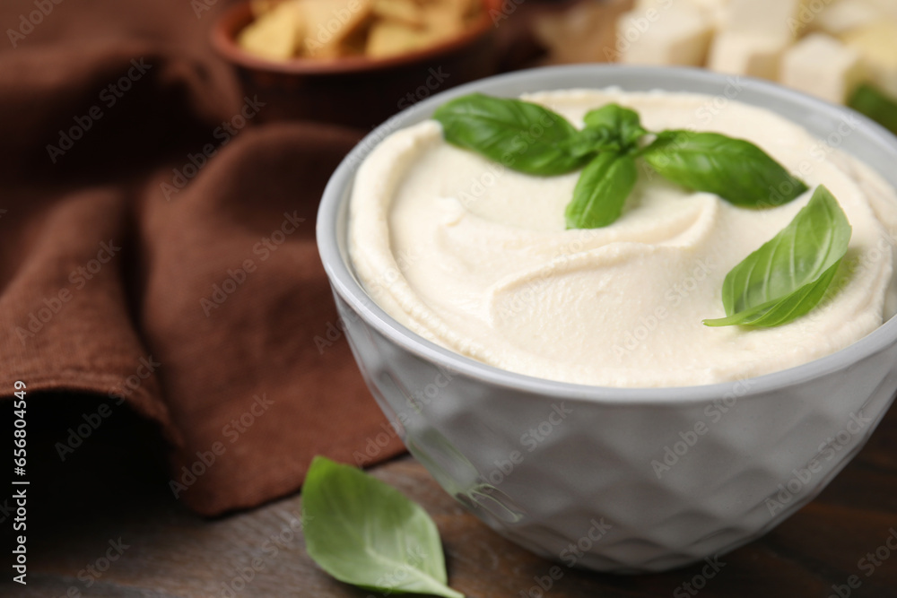 Delicious tofu sauce and basil leaves in bowl on wooden table, closeup. Space for text Delicious tofu sauce and basil leaves in bowl on wooden table, closeup. Space for text