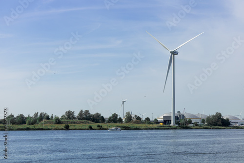 A wind generator stands in the Netherlands near a river A sunny summer day. Ecology, green energy and saving the planet. 