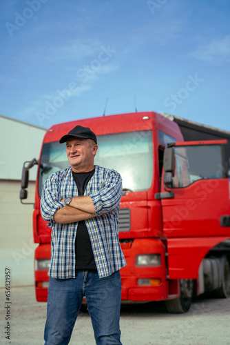 Middle age Caucasian truck driver standing confident in front of his vehicle, vertical 