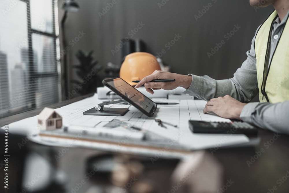 Architect, Engineering working with house drawings inspection on tablet in the office. Engineer, Architect, Industry and factory concept. Architect, Engineering working with house drawings inspection on tablet in the office. Engineer, Architect, Industry and factory concept.