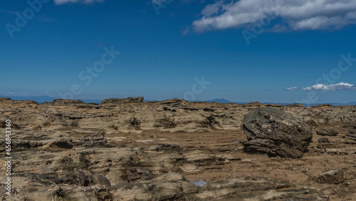 The seabed was exposed at low tide. Puddles of water on the rocks. Clam shells are visible on boulders. Clouds in the blue sky. Madagascar. Nosy Be island