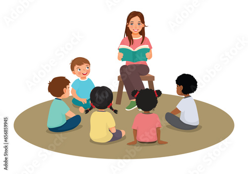 Young female teacher explaining lesson telling story to students sitting on the floor

