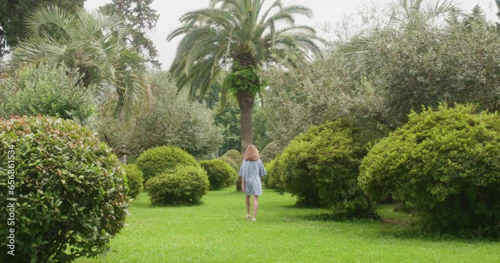 Rear view of teenage girl walking on grassy field against trees. Female ...