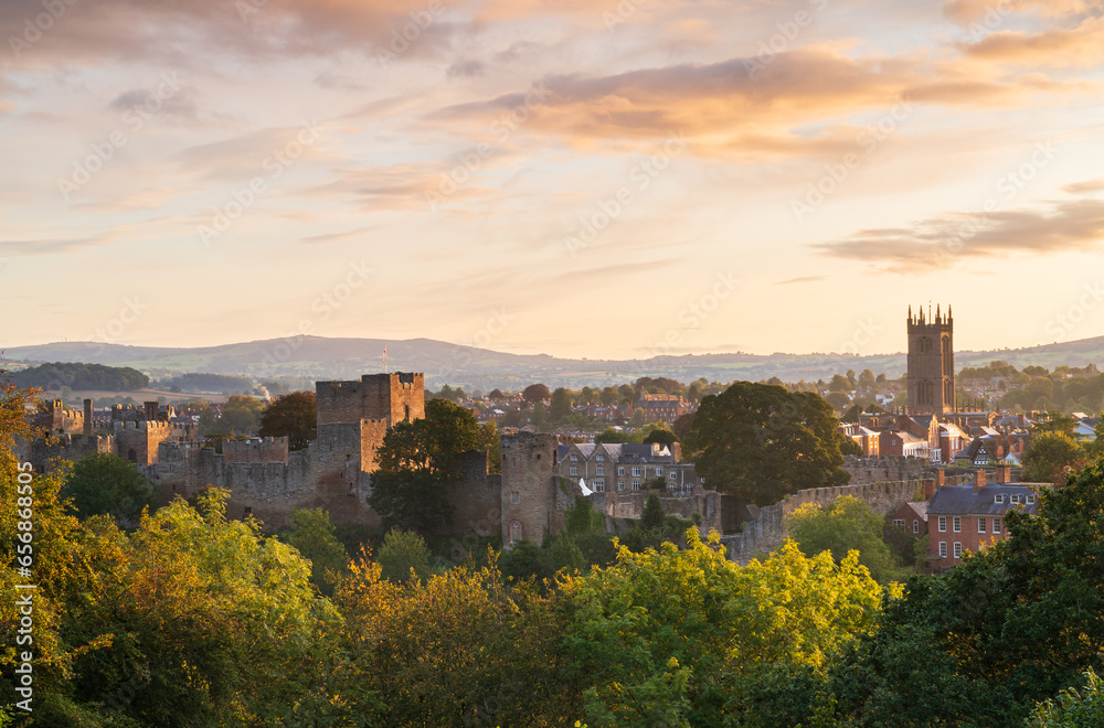 Sunrise colours in the Town of Ludlow in Shropshire, UK with the castle and buildings in the midground and the Clee Hills on the horizon