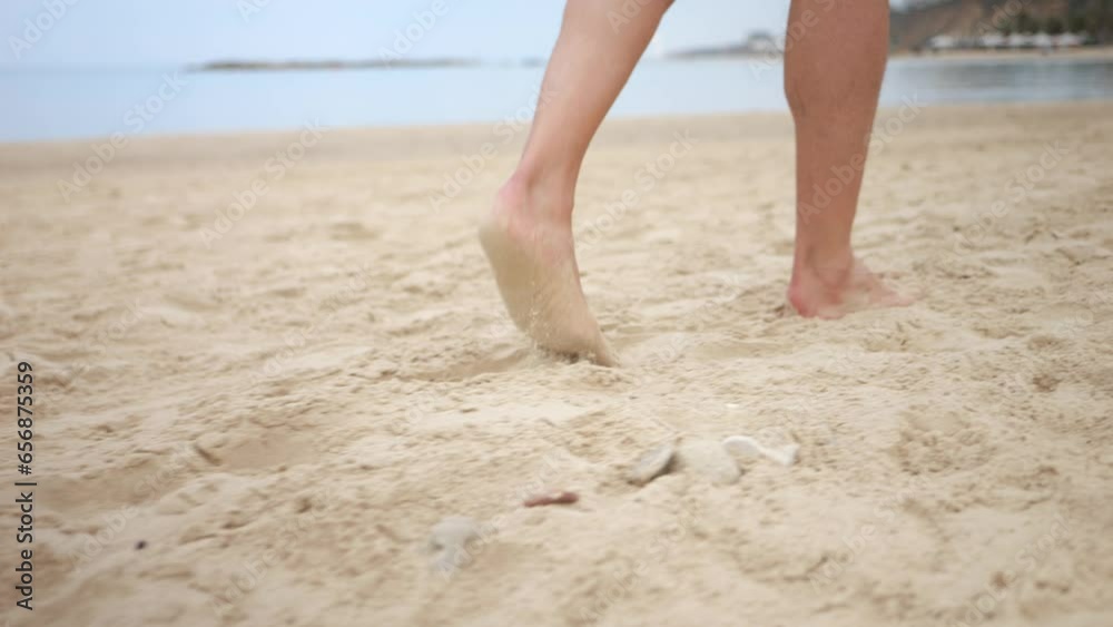 Tracking handheld shot of person’s legs and barefeet walking across sandy beach Tracking handheld shot of person’s legs and barefeet walking across sandy beach