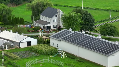Solar panels on barn of American farm. Aerial establishing shot of homestead with garden, Amish wash clothes line, and house.