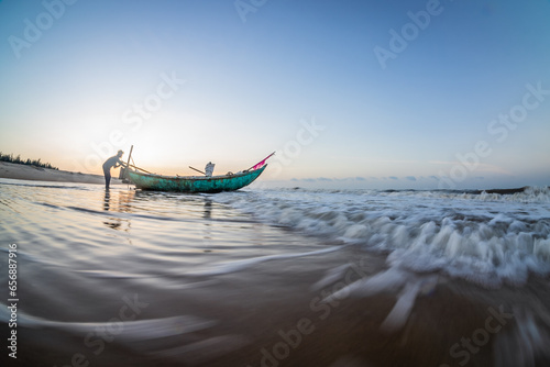 Silhouettes of fishermen on the beach pushing wooden boats out to sea to fish wooden boats on Ho Coc Vung Tau beach