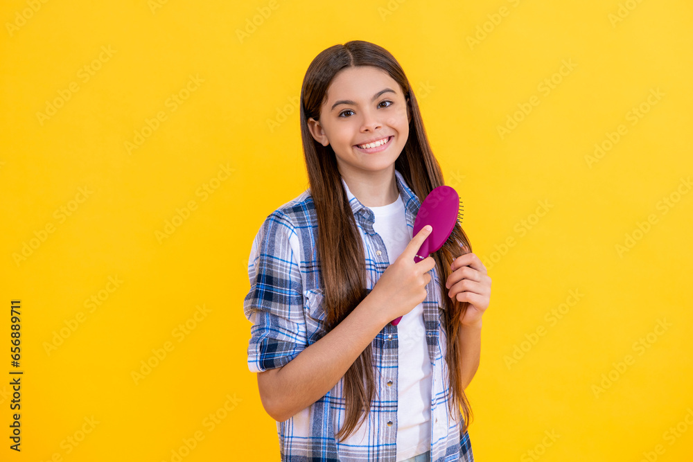 smiling teen girl with hairbrush. teen girl using a hairbrush to style