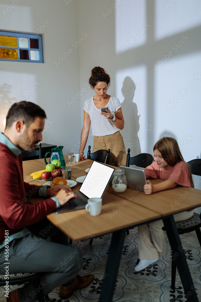 Family using electronic devices in the dining room Family using electronic devices in the dining room