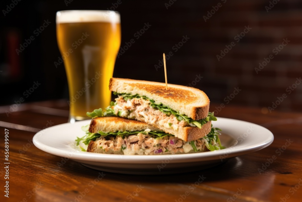 tuna salad sandwich on a bar coaster against a brick wall
