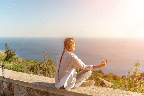 Yoga woman mountains. Profile of a woman doing yoga in the top of a cliff in the mountain. Woman meditates in yoga asana Padmasana photo