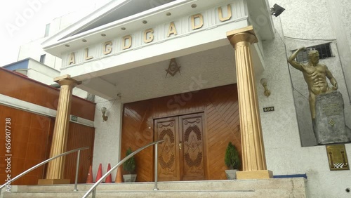 A Masonic lodge. Two golden pillars on each side. On the top the acronym which reads ALGDGADU. Large wooden doors to the temple and above the masonic G. Located in Lima, Peru. photo