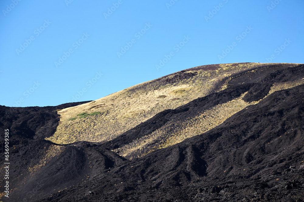 Mount Etna, Sicily, Italy. Slopes of volcano are covered with volcanic ash and frozen lava. Summer mountain landscape on sunny day