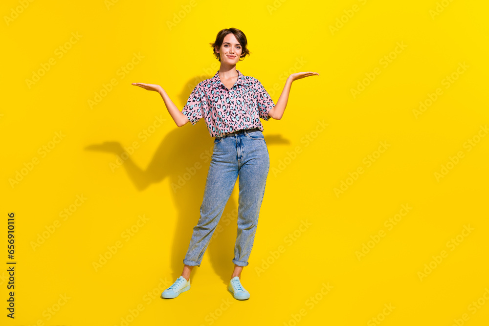 Full size portrait of pretty positive girl arms hold demonstrate empty space proposition isolated on yellow color background Full size portrait of pretty positive girl arms hold demonstrate empty space proposition isolated on yellow color background