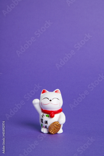 a trendy Maneki-neko plastic cat on violet background © Loulou02