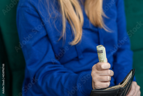 Kobieta trzyma pieniądze w ręce wyciągnięte z portfela 