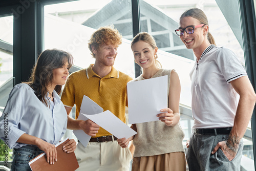 Εκτύπωση καμβά cheerful colleagues in smart casual attire looking at work papers with glass bac
