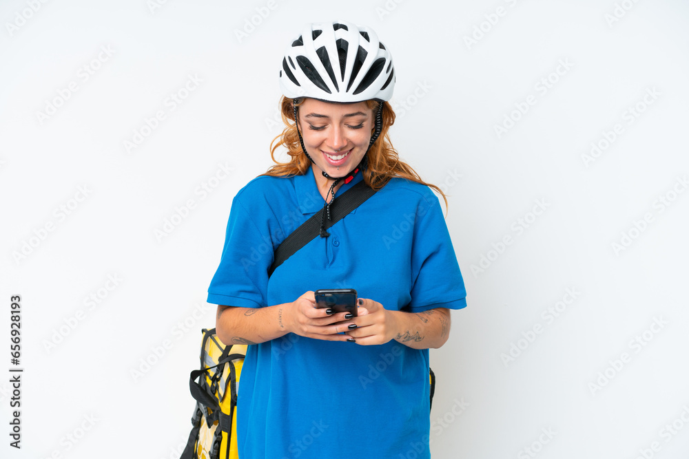 Young caucasian woman with thermal backpack isolated on white background sending a message with the mobile Young caucasian woman with thermal backpack isolated on white background sending a message with the mobile