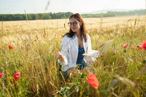 Smiling environmentalist examining plants at field on sunny day
