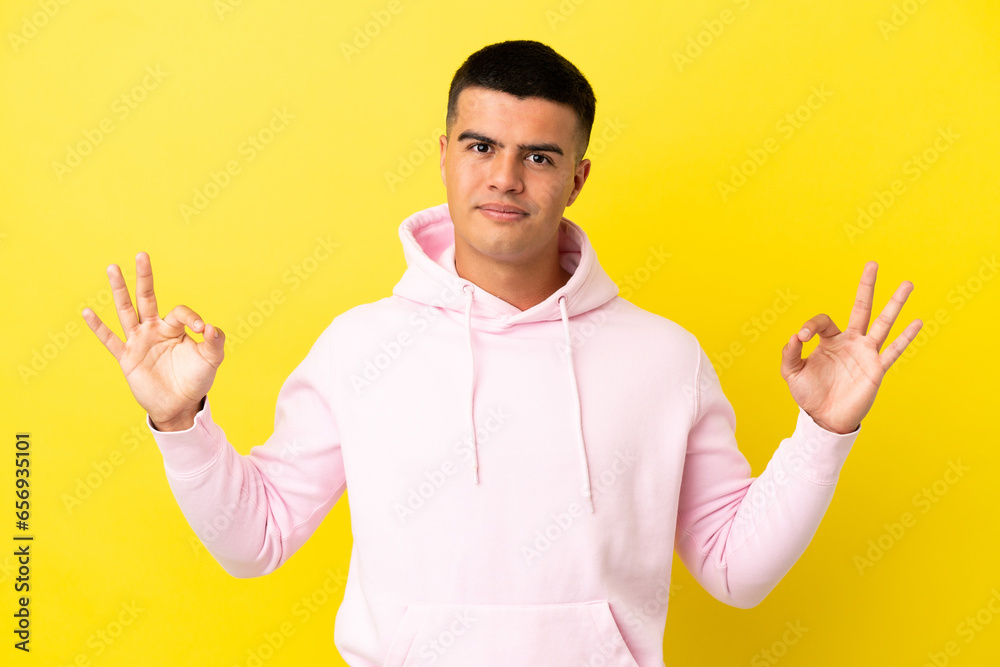 Young handsome man over isolated yellow background in zen pose Young handsome man over isolated yellow background in zen pose