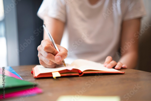 Businesswoman writing in diary with pen photo