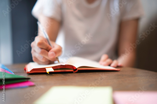 Businesswoman writing in diary on table photo