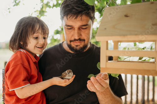 Excited son holding sparrow near birdhouse photo