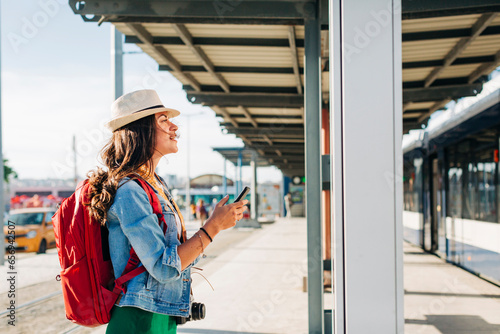 Young woman wearing hat going through route map at tram station